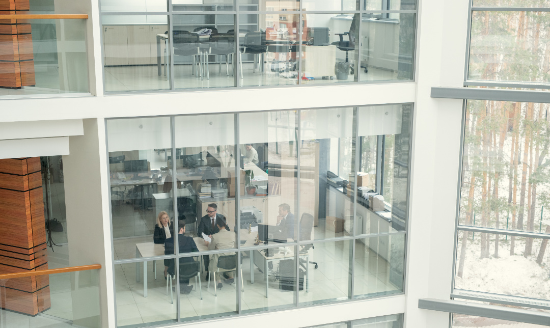 Above view of business people sitting at one table and working behind glass wall in office lobby