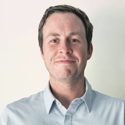 Young smiling head and shoulder portrait of a Caucasian man with brown short hair wearing a white shirt